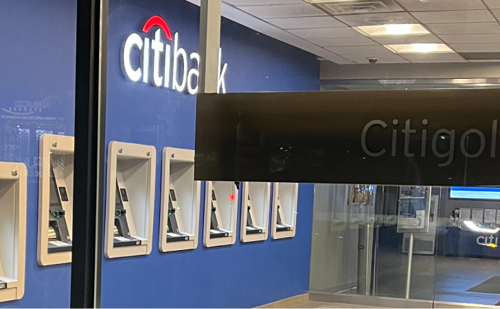 Inside of Citibank, large Citibank logo on wall overlooking several banking kiosks.