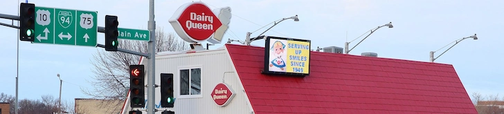 Dairy Queen restaurant showcasing a huge logo above a white building with a red roof.