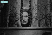 Animated black and white gif of a woman peaking through curtains.